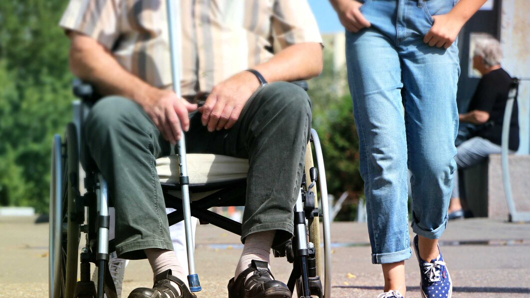 Persoon in rolstoel met begeleider die ernaast loopt